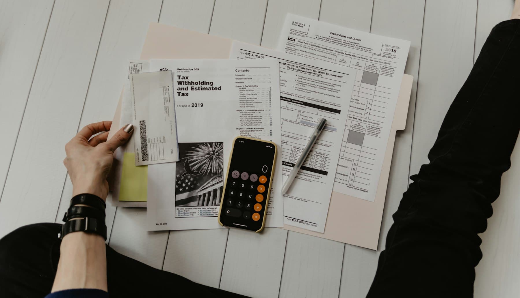 Persona revisando facturas con una calculadora y un teléfono